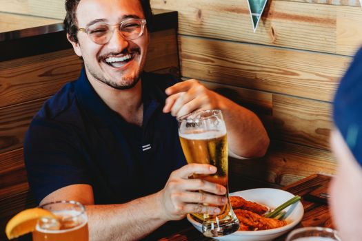 a customer at miller's ale house holding a beer enjoying with his friends watching football